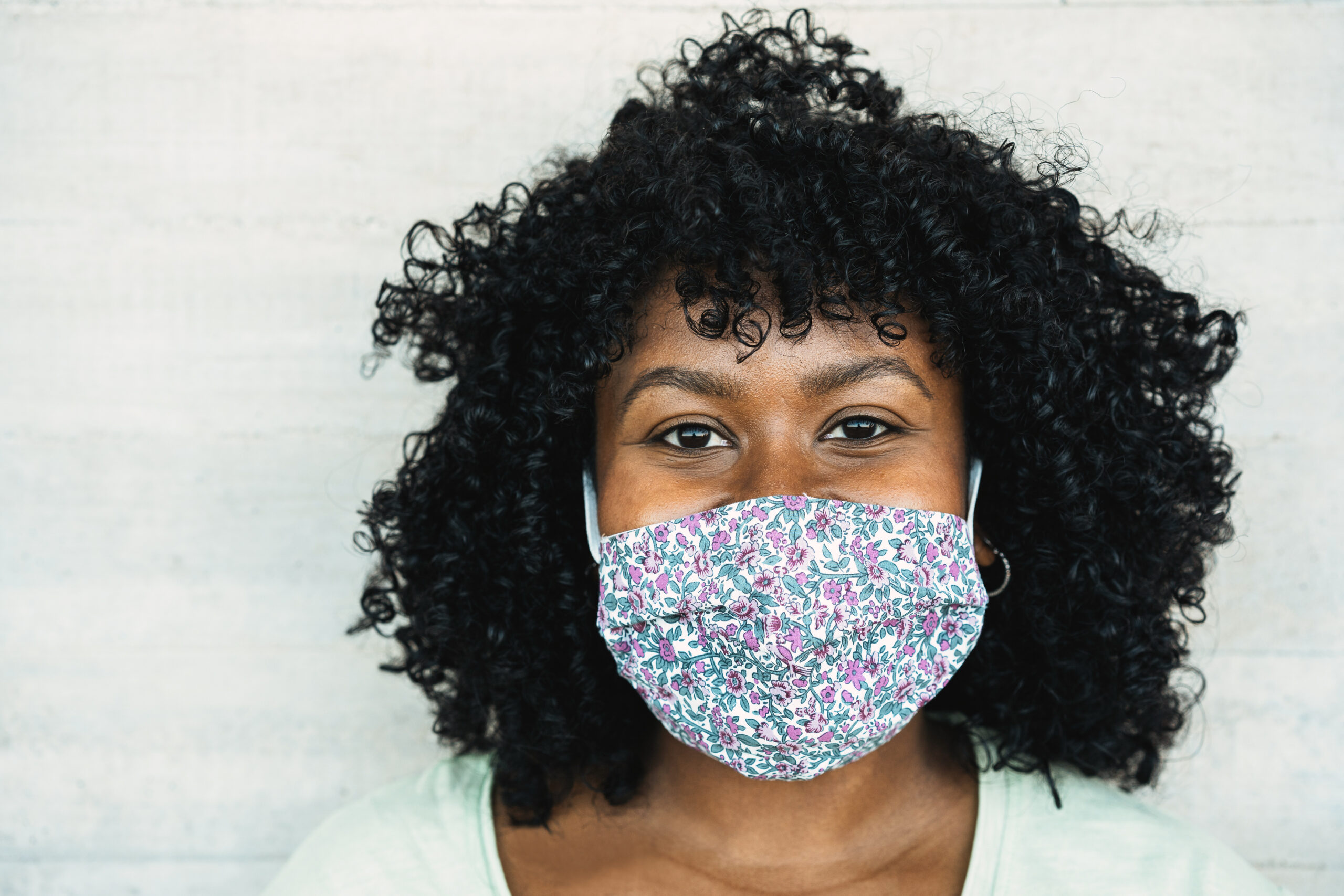 Happy black girl smiling under protective face mask - Young millennial person during coronavirus lifestyle - Health care and happiness concept - Focus on face Happy black girl smiling under protective face mask - Young millennial person during coronavirus lifestyle - Health care and happiness concept - Focus on face